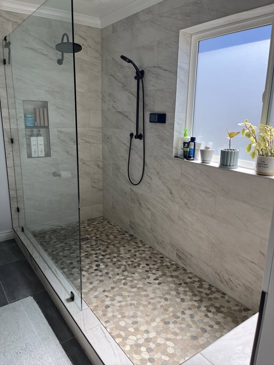 A spotless tiled shower cleaned by With Heart Housekeeping